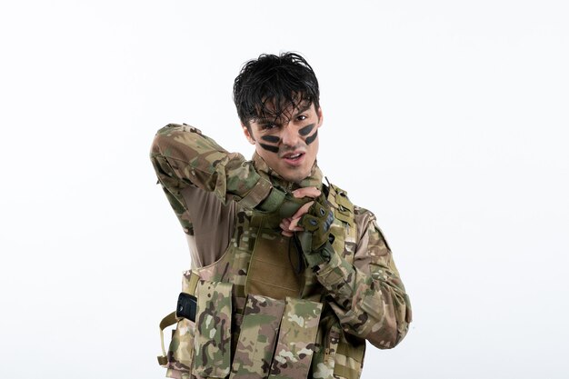 Portrait de jeune soldat en camouflage sur mur blanc