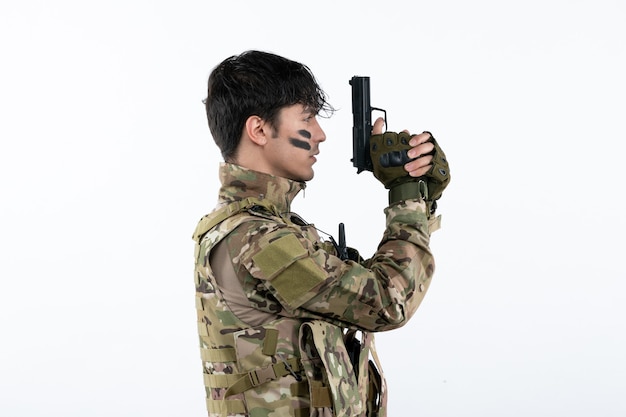 Portrait de jeune soldat en tenue de camouflage avec un mur blanc tourné en studio d'armes à feu