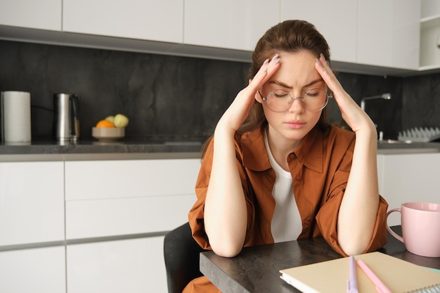 Photo gratuite portrait d'une jeune travailleuse fatiguée en lunettes tenant les mains sur la tête souffrant d'une migraine douloureuse