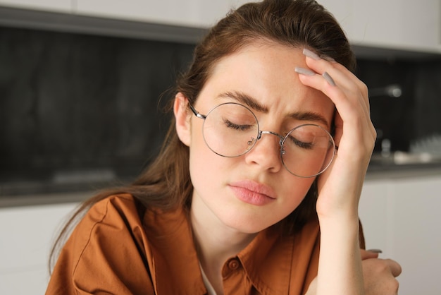 Photo gratuite portrait d'une jeune travailleuse fatiguée en lunettes tenant les mains sur la tête souffrant d'une migraine douloureuse