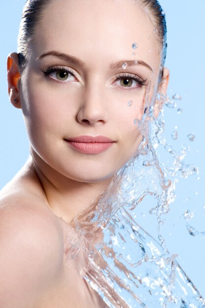 Portrait de jeune visage féminin avec des éclaboussures d'eau - fond bleu