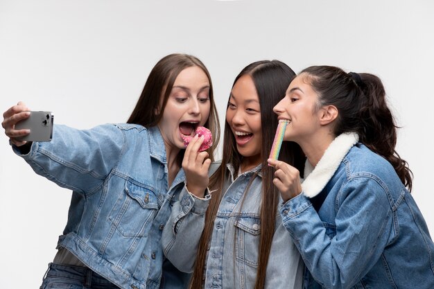 Portrait de jeunes adolescentes mangeant un beignet