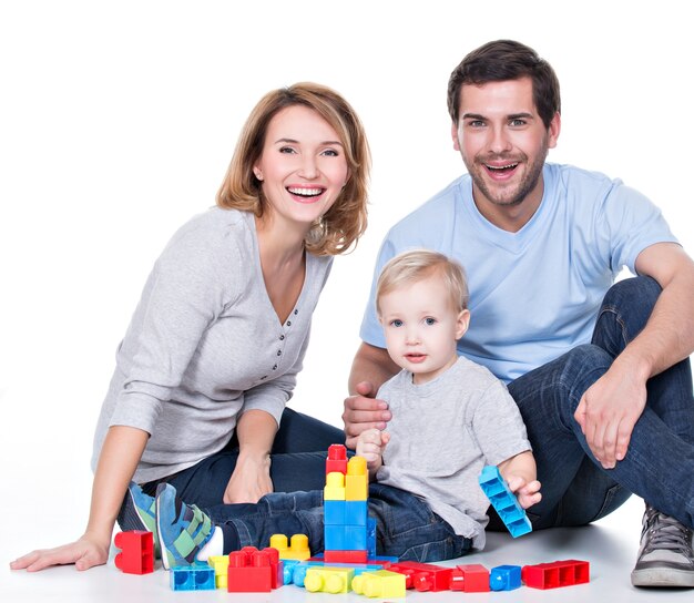 Portrait de jeunes parents souriants heureux jouant avec un bébé - isolé sur blanc