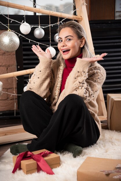 Portrait de jolie femme assise avec des cadeaux de Noël