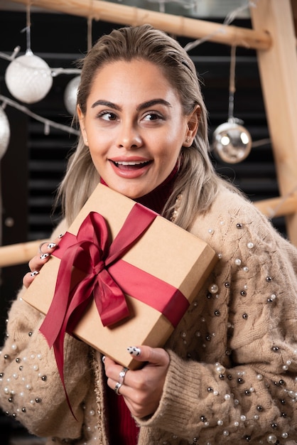 Portrait de jolie femme assise et tenant un cadeau de Noël