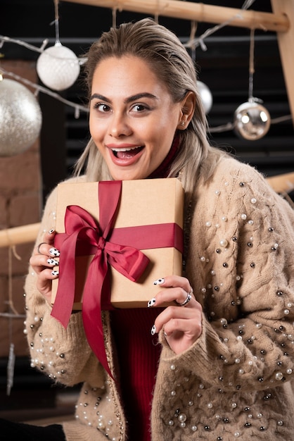 Portrait de jolie femme assise et tenant un cadeau de Noël
