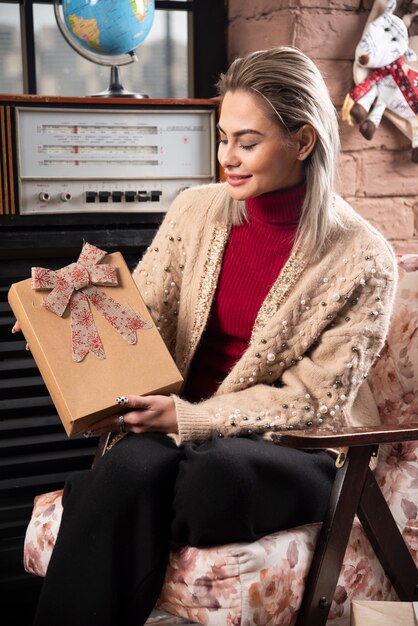 Portrait de jolie femme assise et tenant un cadeau de Noël