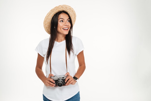 Portrait d'une jolie femme au chapeau tenant un appareil photo