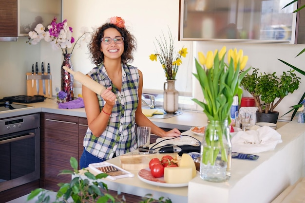 Portrait de jolie femme brune aux cheveux bouclés dans une cuisine à domicile avec beaucoup de fleurs.