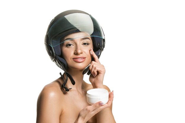 Portrait de jolie femme en casque de moto sur mur blanc. Concept de beauté, de peau et de protection du visage