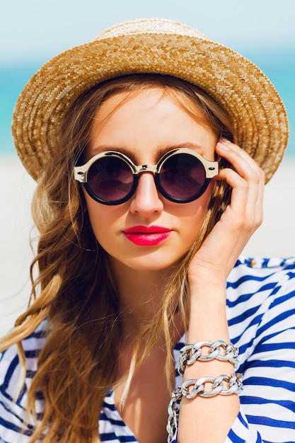 Portrait de jolie femme élégante blonde en chapeau de paille et lunettes de soleil