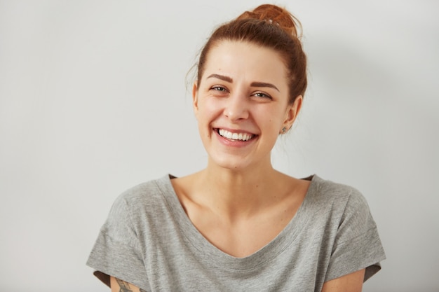 Portrait de jolie femme mignonne riant ou souriant sur un mur gris