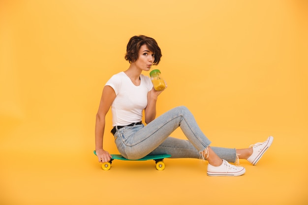 Portrait d'une jolie femme souriante assise sur une planche à roulettes