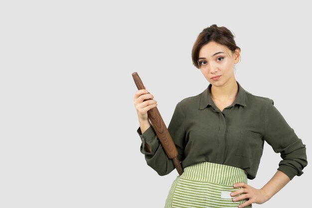 Portrait de jolie femme en tablier tenant un rouleau à pâtisserie. photo de haute qualité