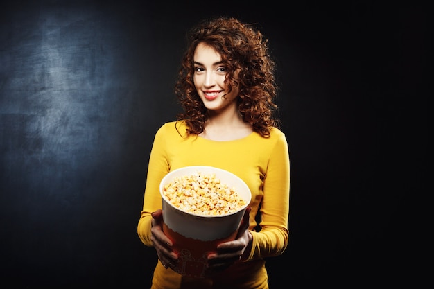 Portrait de jolie femme traitant de pop-corn avec un sourire joyeux