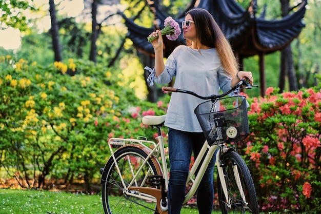 Portrait de jolie femme avec vélo de ville près du pavillon chinois traditionnel dans un parc.