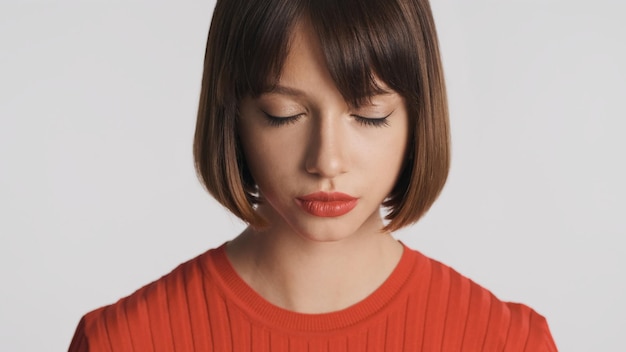 Photo gratuite portrait d'une jolie fille brune aux cheveux bob et aux lèvres rouges fermant rêveusement les yeux sur fond blanc