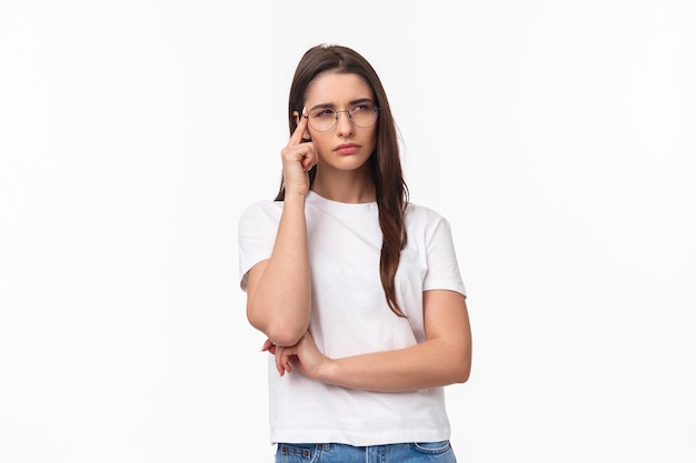 Portrait de jolie fille brune douteuse à la recherche concentrée et suspecte