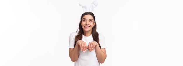 Portrait d'une jolie fille européenne drôle avec des oreilles de lapin imitant un lapin se tenant la main comme des pattes et