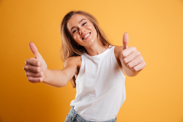 Portrait d'une jolie fille gaie montrant les pouces vers le haut