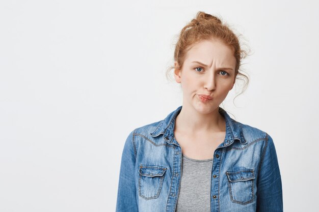 Portrait de jolie fille rousse caucasienne malheureuse, fronçant les sourcils et plissant les yeux tout en étant concerné ou en hésitant