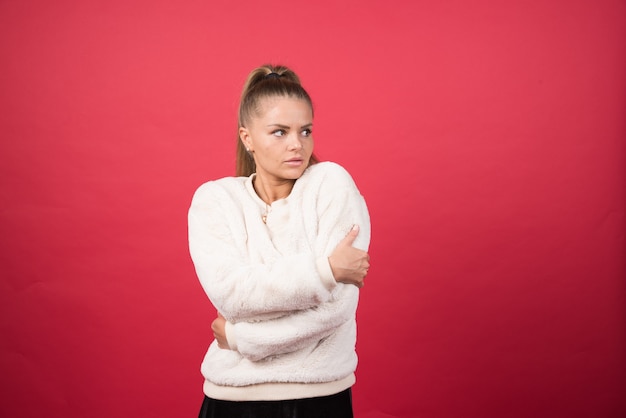 Photo gratuite portrait d'une jolie fille se serrant isolé sur fond rouge