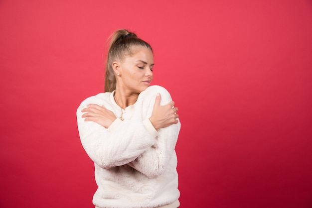 Photo gratuite portrait d'une jolie fille se serrant isolé sur mur rouge