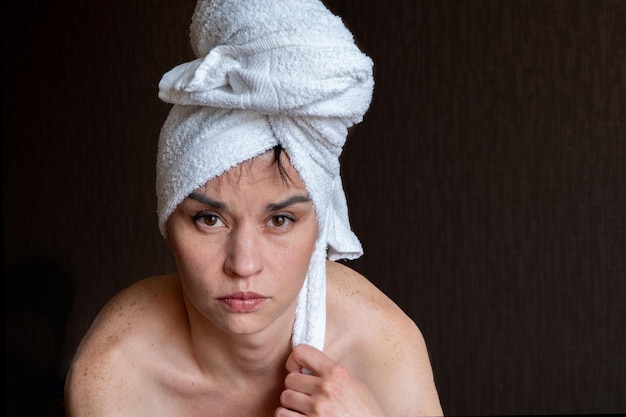 Portrait d'une jolie fille avec une serviette blanche sur ses cheveux sur fond sombre après spa.