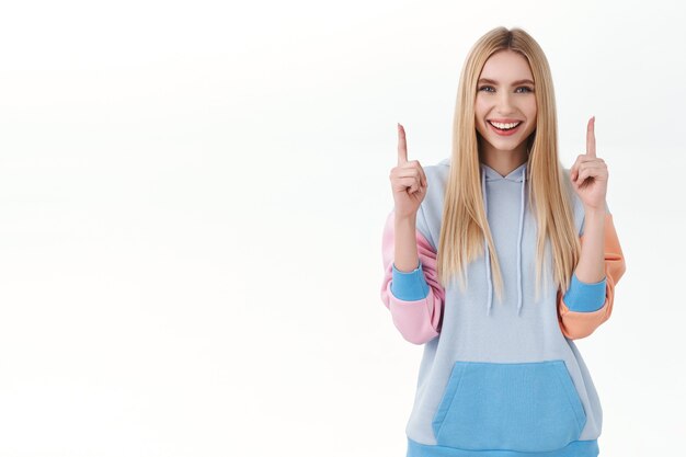 Portrait de jolie fille souriante et heureuse aux longs cheveux blonds, donne des conseils