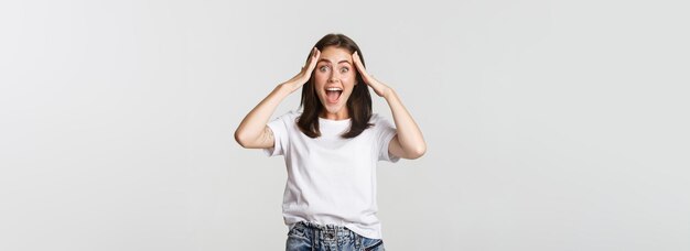 Portrait d'une jolie fille surprise qui a l'air excitée et souriante étonnée