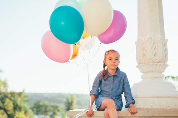 Portrait de jolie fille tenant des ballons colorés dans le parc de la ville