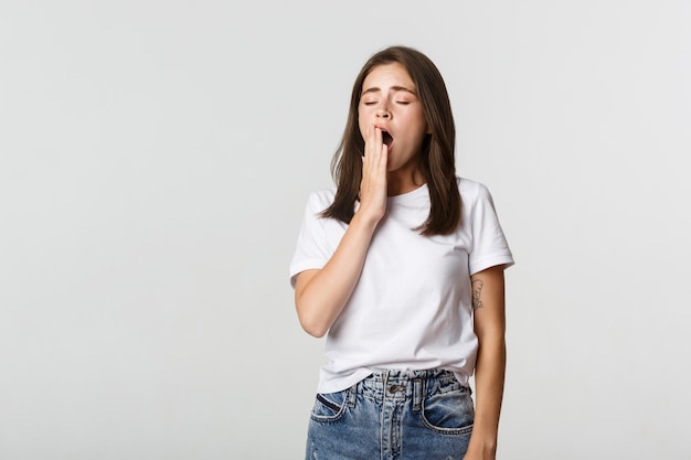 Portrait de jolie jeune étudiante bâillement fatigué, se sentir somnolent, blanc