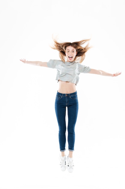 Photo gratuite portrait d'une jolie jeune femme heureuse sautant avec les mains levées