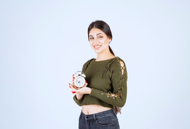 Portrait de jolie jeune femme montrant le réveil.