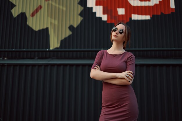 Portrait de jolie jeune femme posant contre un mur sombre