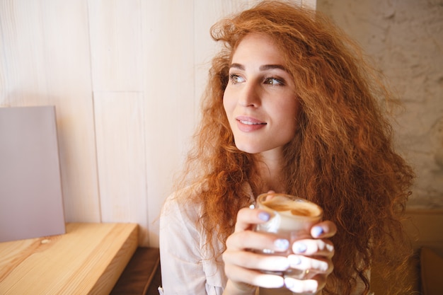 Portrait d'une jolie jeune femme sentant sa boisson au café