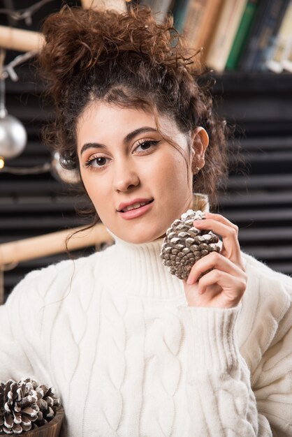 Photo gratuite portrait d'une jolie jeune femme tenant des pommes de pin dans ses mains