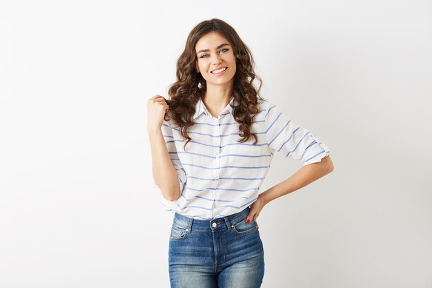 Portrait de jolie jeune femme vêtue de style d'été de mode décontractée, chemise et jeans, cheveux bouclés, souriant, regardant à huis clos, beau modèle isolé, dents blanches, joli visage, pose détendue