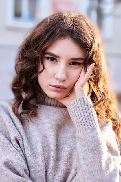 Portrait d'une jolie jeune fille avec des boucles au coucher du soleil