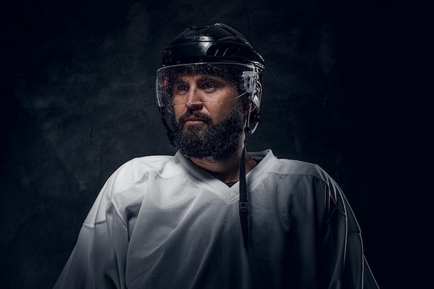 Photo gratuite portrait d'un joueur de hockey pensif en uniforme blanc et casque de protection.