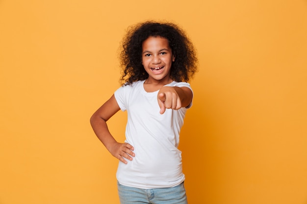 Portrait d'une joyeuse petite fille africaine pointant le doigt