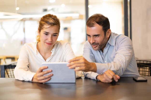 Portrait de joyeux collègues sur une tablette numérique au café