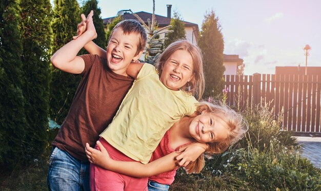 Portrait de joyeux petits amis s'amusant dans la cour. Trois mignons petits amis se câlinant et jouant.