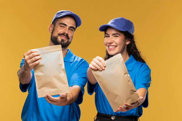 Portrait de livreurs masculins et féminins distribuant des sacs en papier