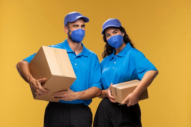 Photo gratuite portrait de livreurs masculins et féminins avec des masques médicaux tenant des boîtes en carton