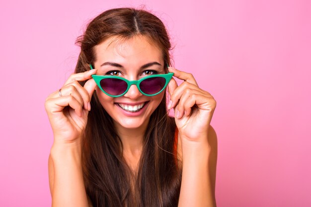 Portrait lumineux de jeune femme brune portant des lunettes de soleil vert oeil de chat à la mode