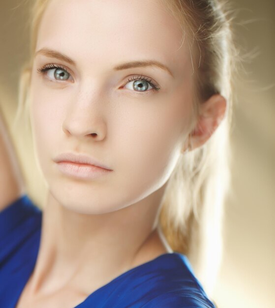 Portrait lumineux à la mode d'une jeune fille blonde en robe bleue.