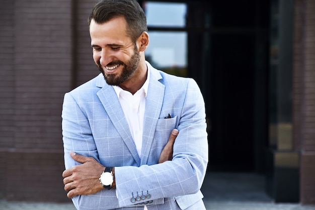 Portrait de mannequin homme d'affaires sexy beau vêtu d'un élégant costume bleu posant sur fond de rue. Métrosexuel