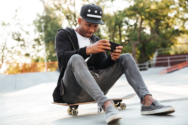 Portrait d'un mec africain jouant sur téléphone mobile