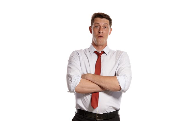 Portrait d'un mec brun aux yeux bruns, vêtu d'une chemise blanche et d'une cravate rouge. Il croisa les mains et posa dans un studio isolé sur fond blanc. Concept de gesticulation et